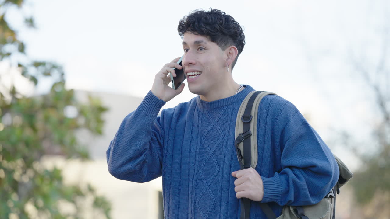 Young latino student talking on phone while walking