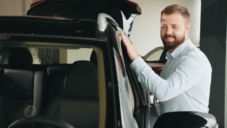 hombre inspeccionando un coche negro en una sala de exposiciones