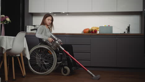 young female with disability vacuums in kitchen carefully