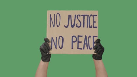 showing cardboard poster with inscription no justice no peace. human rights demonstration. hands holding a poster a green screen, chroma key. close up. slow motion