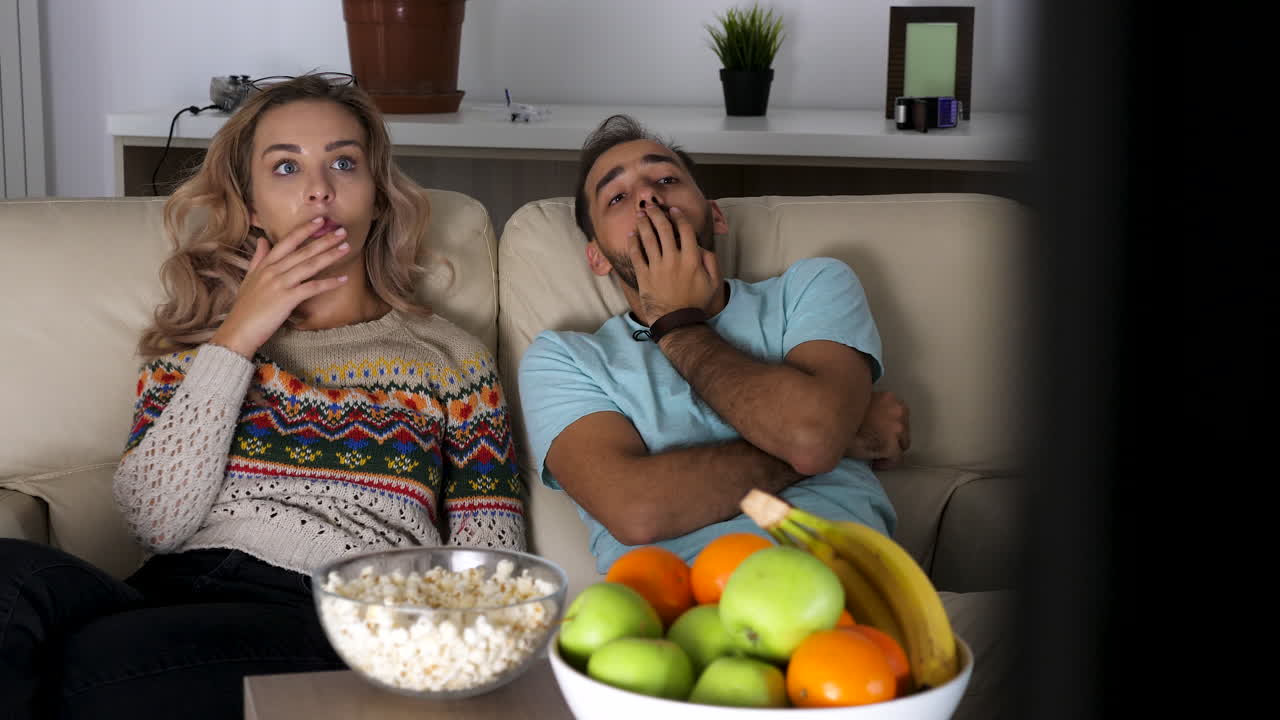 Couple Watching TV with Popcorn and Fruits