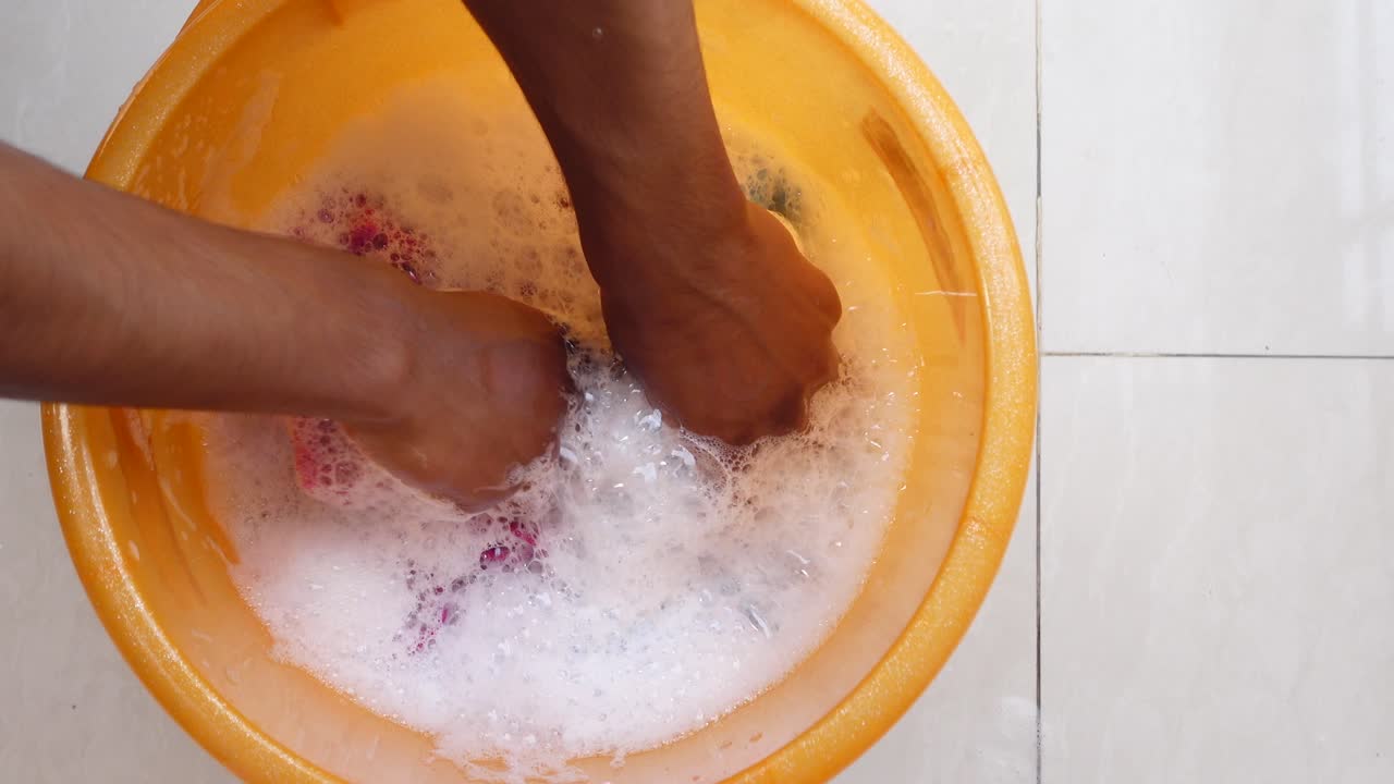 Washing clothes in a plastic bucket