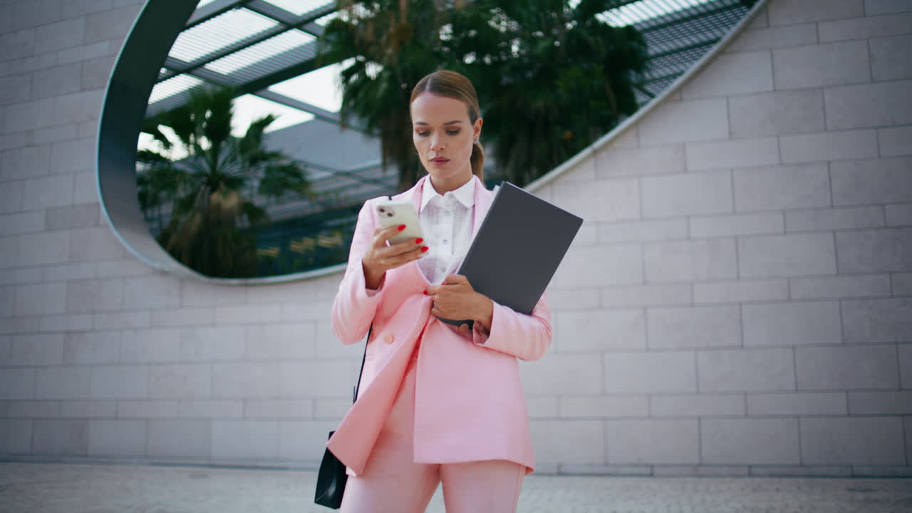 mujer exitosa escribiendo teléfono móvil de pie en el edificio de la ciudad. mujer enviando mensajes de texto