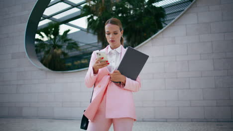 successful lady typing mobile phone standing at town building. woman texting