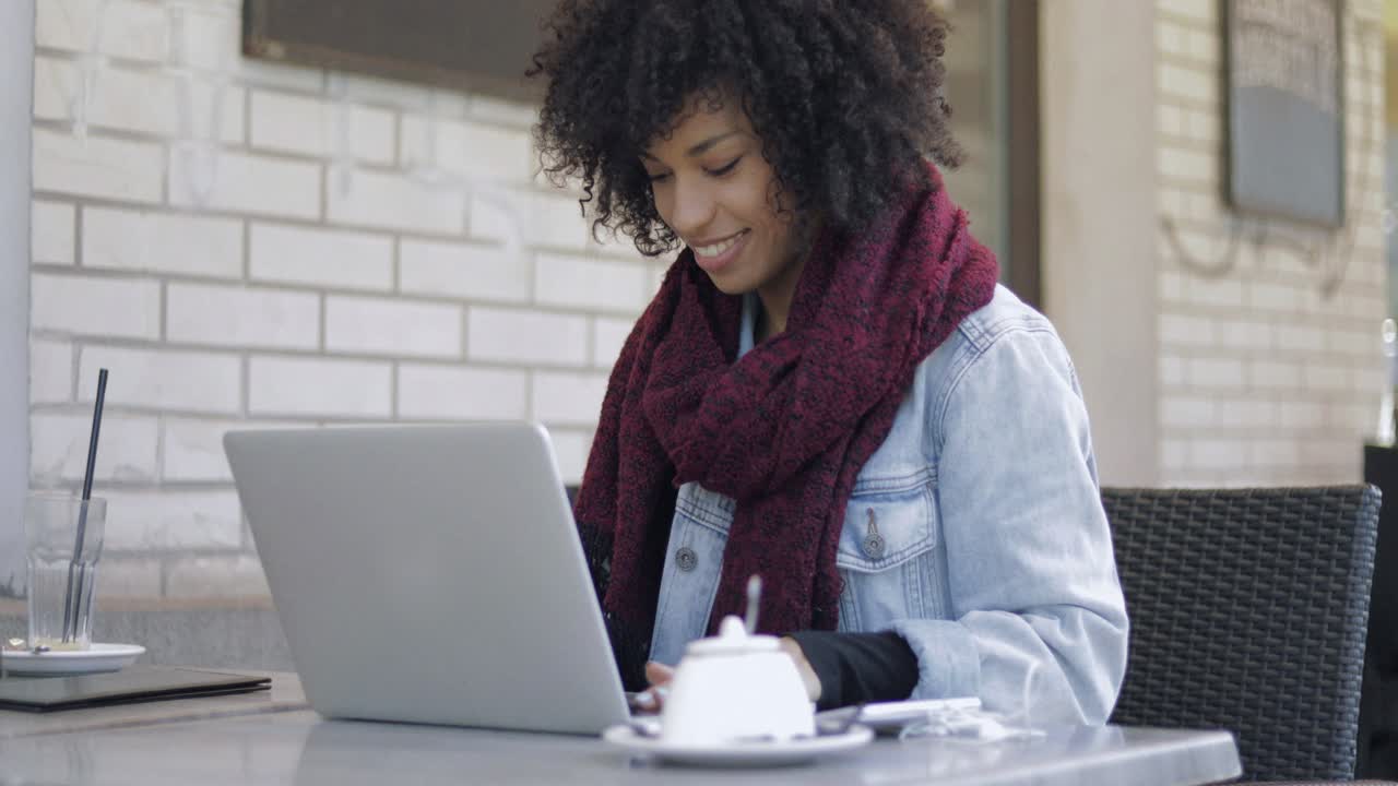 Smiling woman browsing laptop in cafe