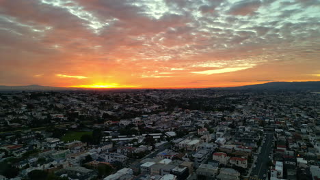 Panoramic-Sunset-landscape-above-American-suburban-city-Aerial-Drone-Golden-Sun-Shining-background,-streets,-houses-and-roofs,-dusk-feeling