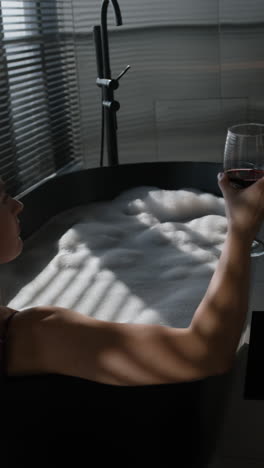 woman enjoying wine in a luxurious black bathtub