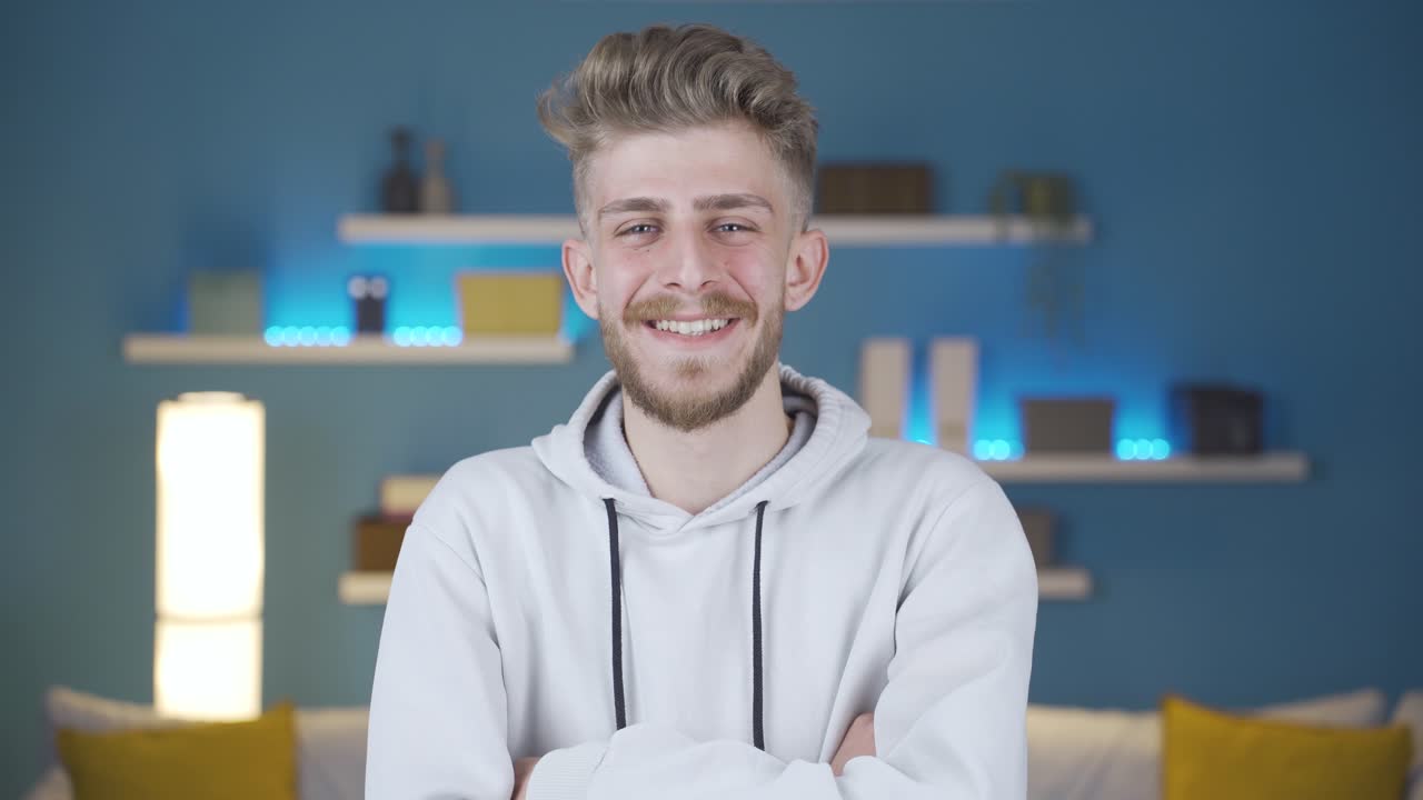 행복한 긍정적인 젊은이가 카메라를 쳐다보고 팔을  ⁇ 는다.