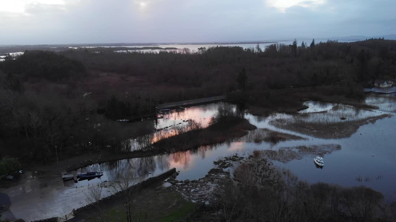 Et filmisk luftfoto af Lough Corrib-kystlinjen i Cong, County Mayo, med roligt vand, små både og en dramatisk solnedgangsrefleksion. Perfekt til rejse- og naturdokumentarer.