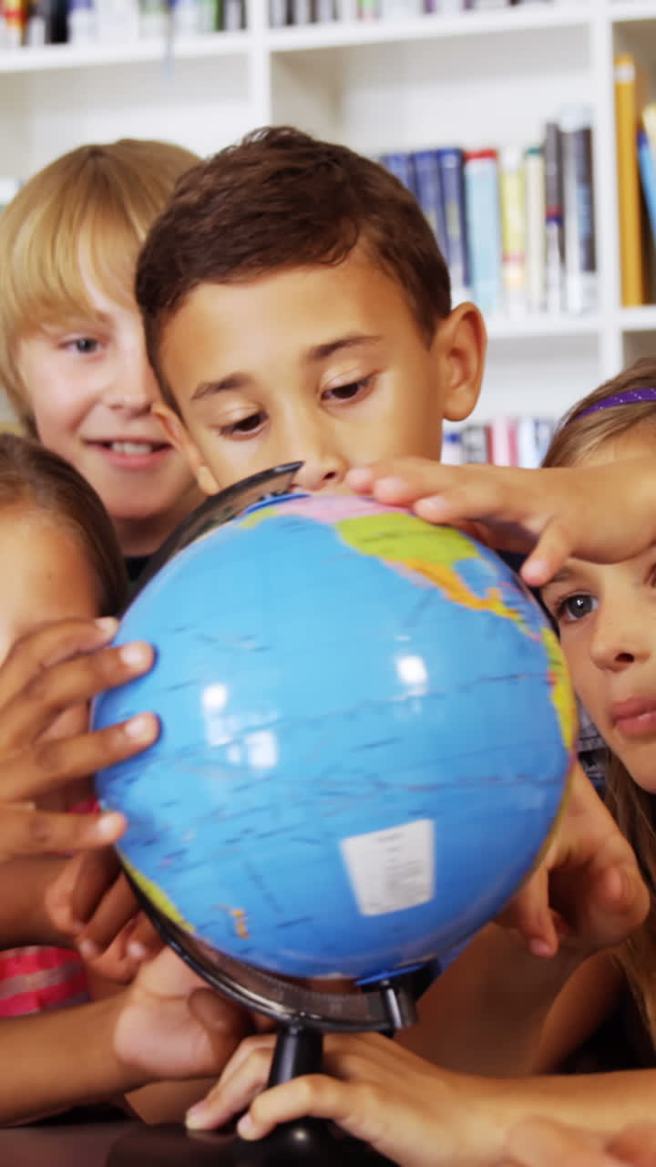 niños de la escuela estudiando el globo en la biblioteca