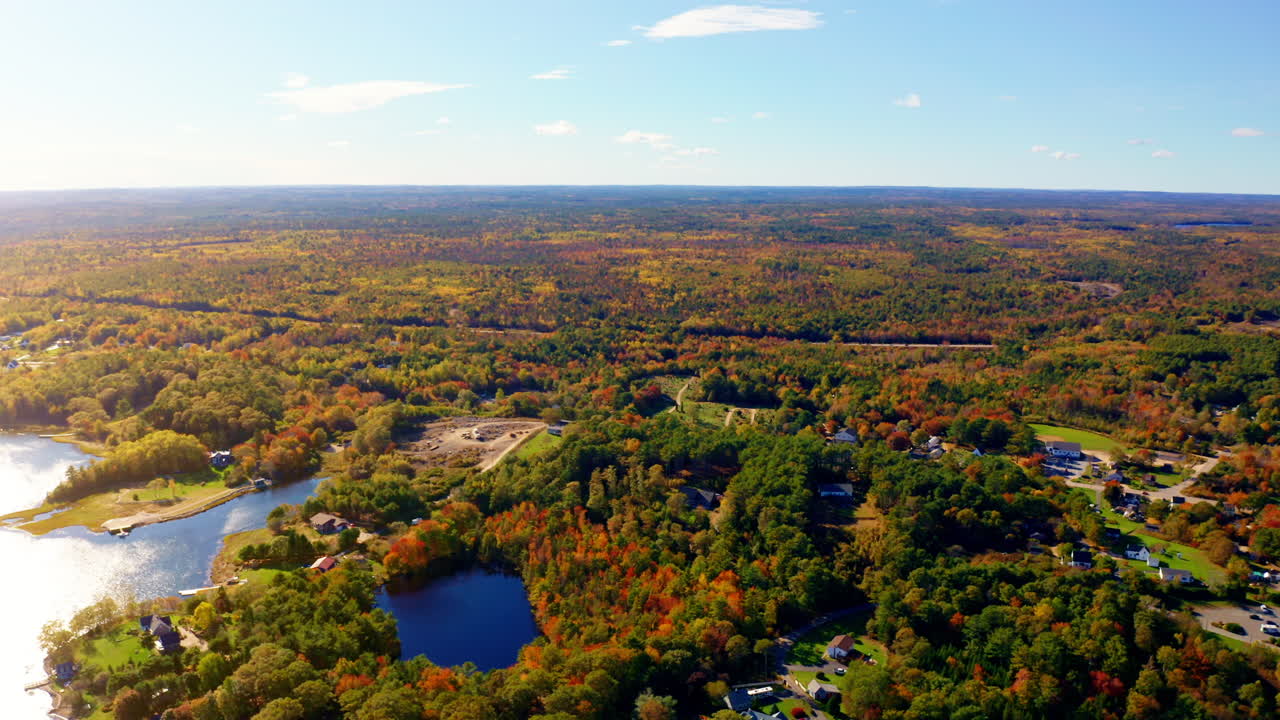 Aerial drone shot over the coastline of Oak Island, Nova Scotia, Canada.
High view of the sea, autumn colorful trees foliage. Picturesque landscape. Fall vibrant colors.