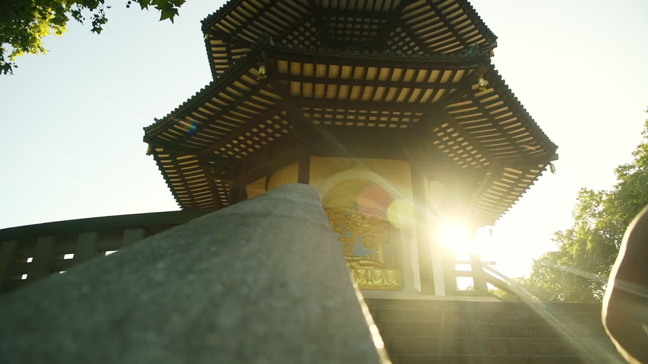A man runs up the stairs in the historic London Battersea Park with the sun bursting around the corner as the camera pans to the right of the scene from a low angle