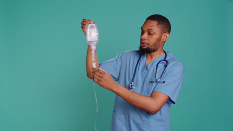 Male-nurse-holding-IV-bag,-preparing-to-use-it-to-administer-fluids