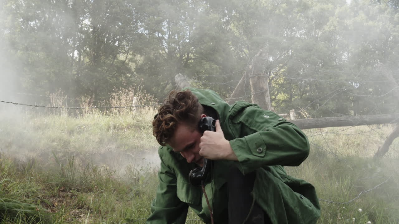 포격 아래에서 도움을 요청하는 젊은 남성 군인 전화