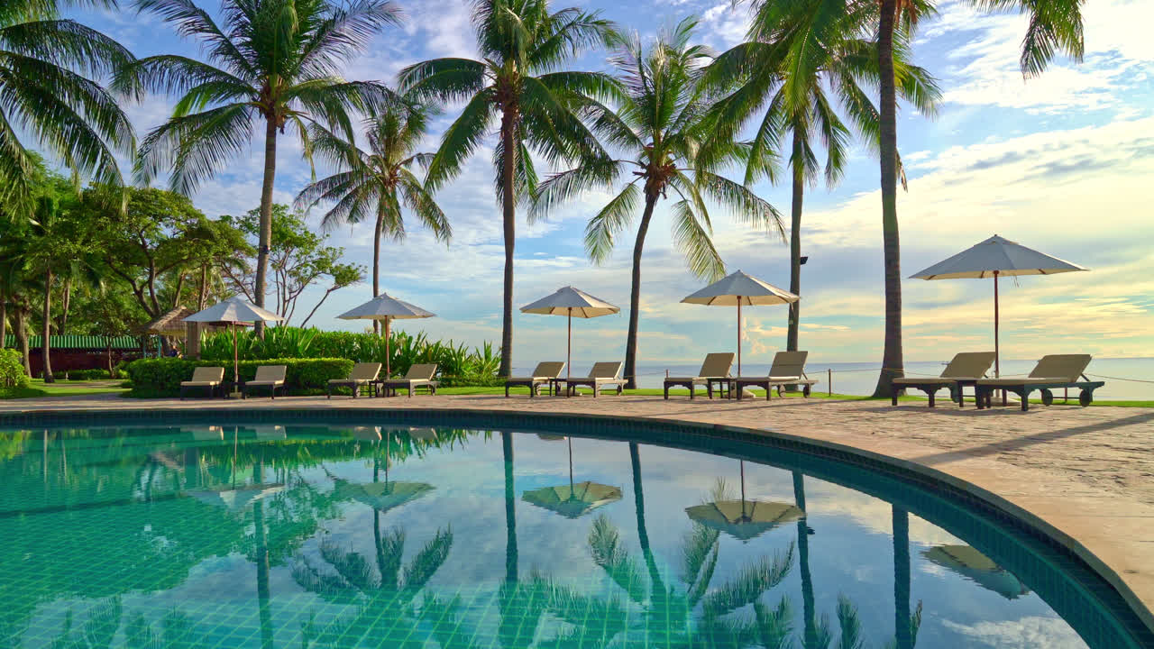 hermosa sombrilla y silla de lujo alrededor de la piscina al aire libre en el hotel y resort con palmera de coco en el cielo del atardecer o del amanecer - concepto de vacaciones y vacaciones
