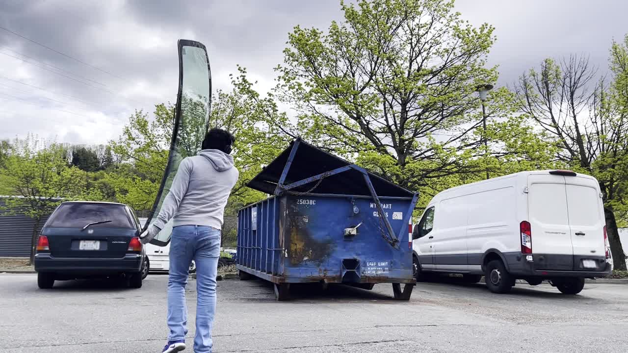 hombre hispano arroja un parabrisas en un contenedor de reciclaje