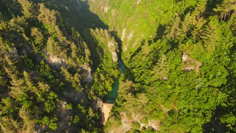 Aerial-descending-fpv-through-canyon-illuminated-by-golden-sunlight-rays