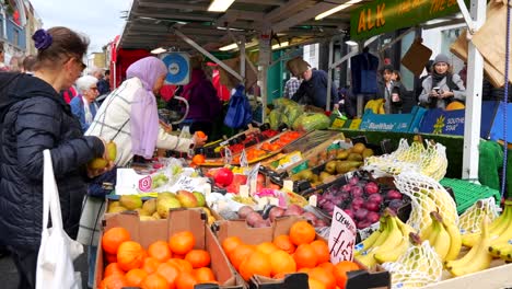 women browse vibrant fruit stands at portobello road market in notting hill, london