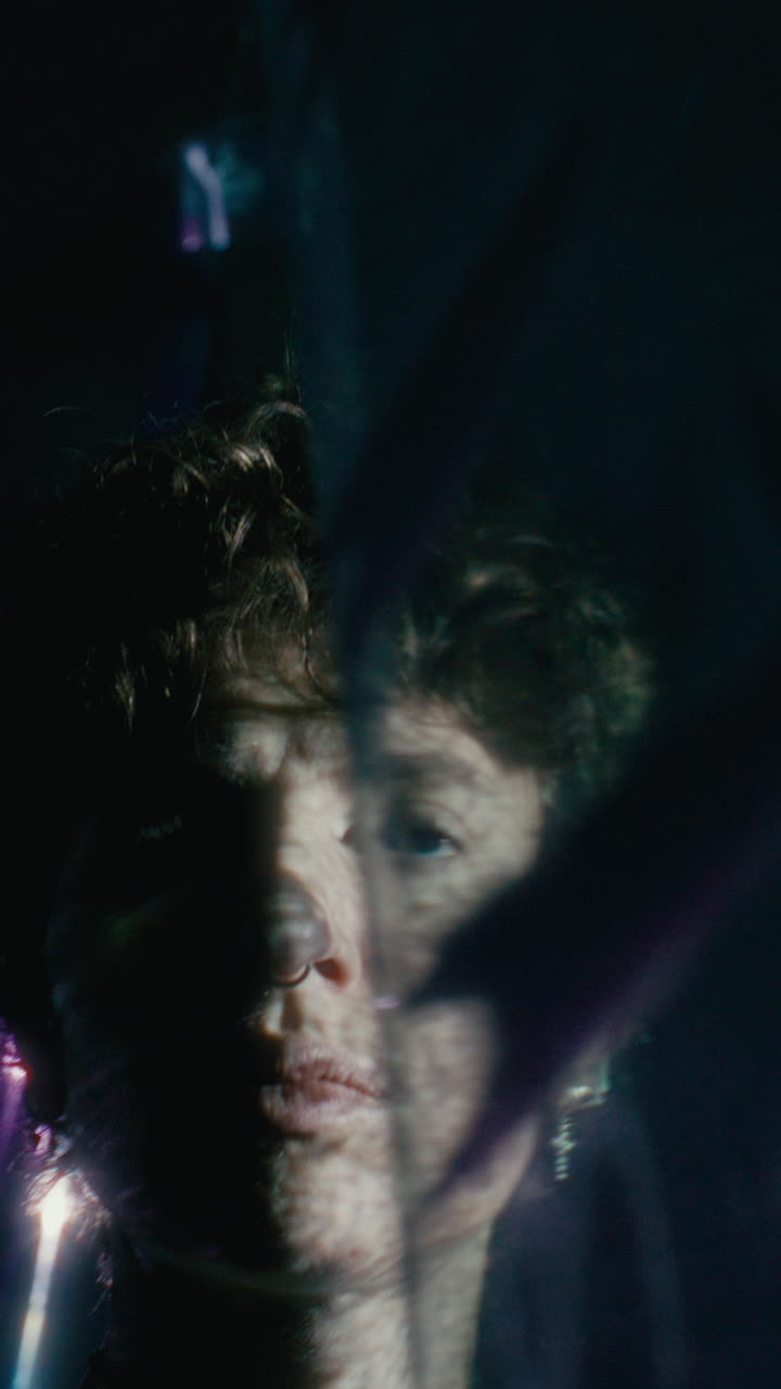 Young Woman Standing behind Plastic Curtain Illuminated by Light