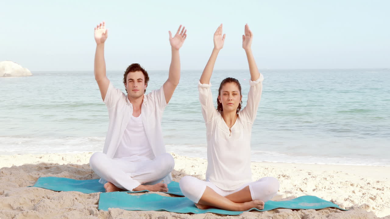 una pareja tranquila meditando en la playa.