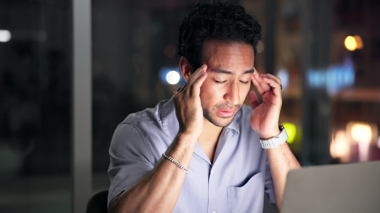 Man Experiencing Headache and Stress While Working Late at Night