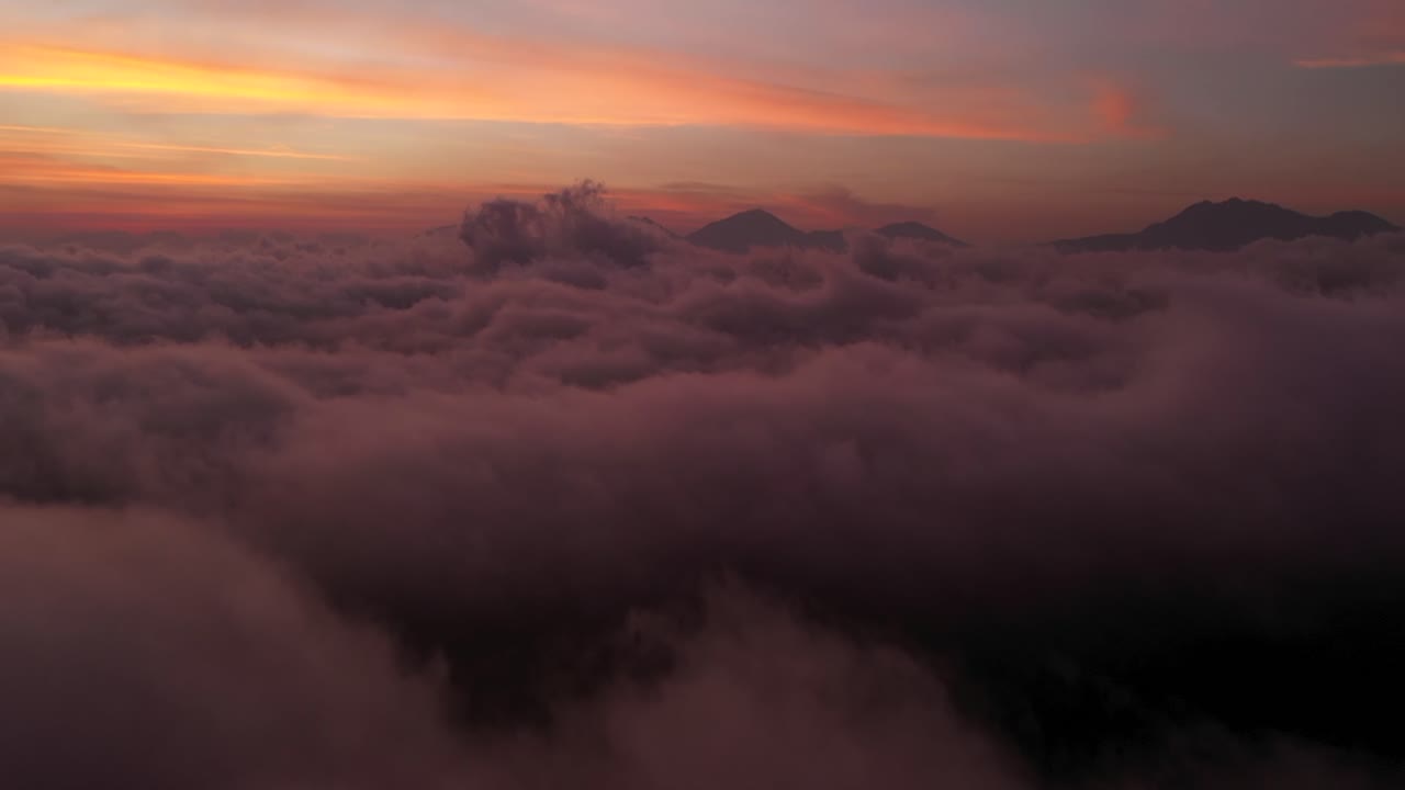la hermosa puesta de sol naranja ardiente más allá de las nubes y los picos montañosos de bali, indonesia - toma aérea