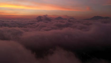 the beautiful fiery orange sunset beyond the clouds and mountain peaks of bali, indonesia - aerial shot