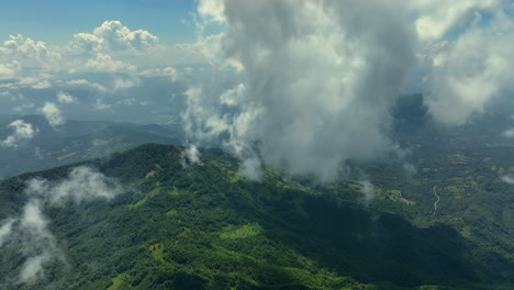 flying trough white fluffy clouds above green mountain peaks