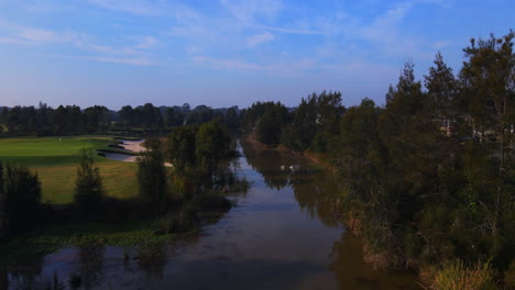 Campo-De-Golf-Verde-Y-Trampas-De-Arena-Junto-A-árboles-Y-Río-Con-Patos-–-Vista-Estática