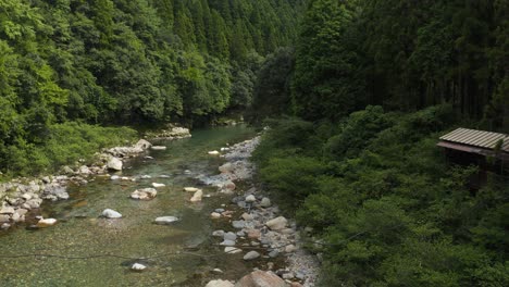 Abandoned-house-along-the-Itadori-River-in-Gifu-Japan,-Pan-Shot