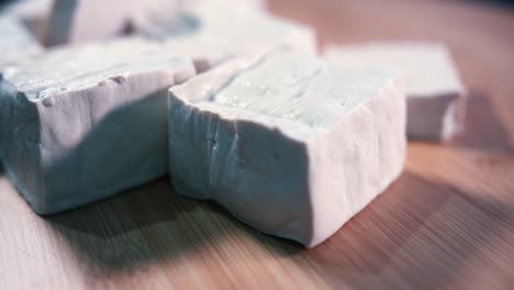 primer plano de tofu en cubos girando sobre una ruleta de madera desde la izquierda