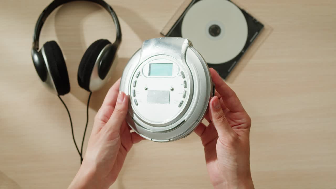 휴대용 cd 플레이어, 헤드폰 및 cd를 책상 위에 들고 있는 손