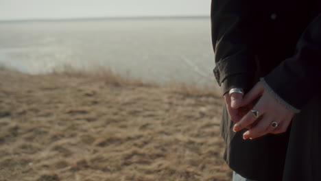 close-up of couple gently holding hands on lakeshore