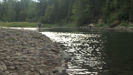 slow motion: a young man skips a rock on a stream in montana