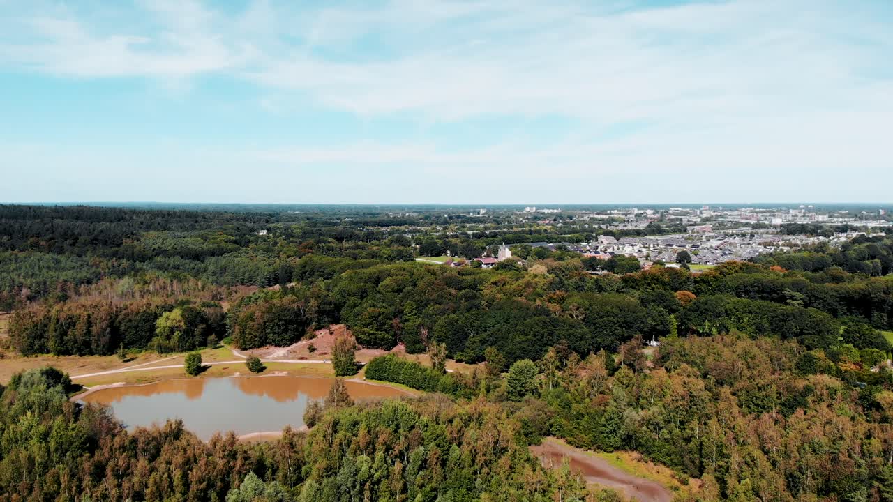 로테르담 삼림 지대의 조감도는 거리에서 교외 도시가 내려다보이는 나무 위로 뒤로 당겨집니다.