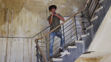 Afroamerikanischer-Mann,-Der-Mit-Einer-Digitalkamera-Fotografiert,-Während-Er-Auf-Einer-Treppe-Steht