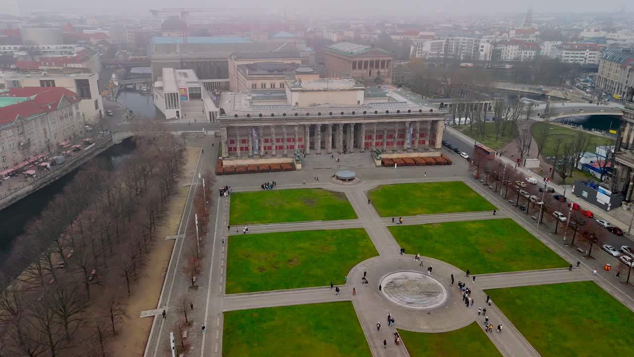 Visitors explore the beautiful parks and historic buildings of Berlin on a foggy day. The serene atmosphere enhances the city's charm with iconic sights visible in the distance