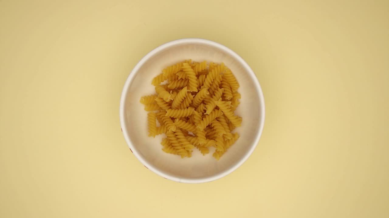 노란색 배경에 있는 접시에 있는 푸실리 - 스 모션