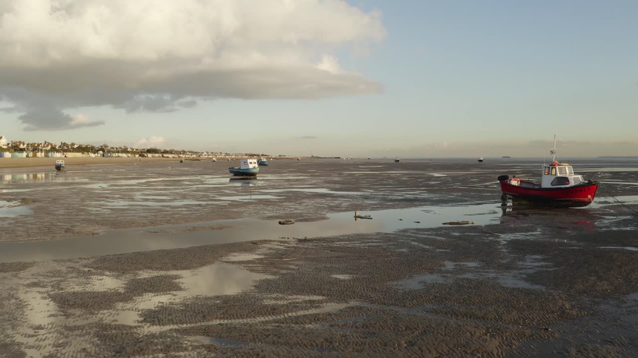 barcos rojos y azules amarrados en la marea baja en un banco de arena en southend, essex
