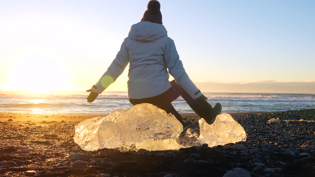Donna seduta su un iceberg su una spiaggia durante il tramonto