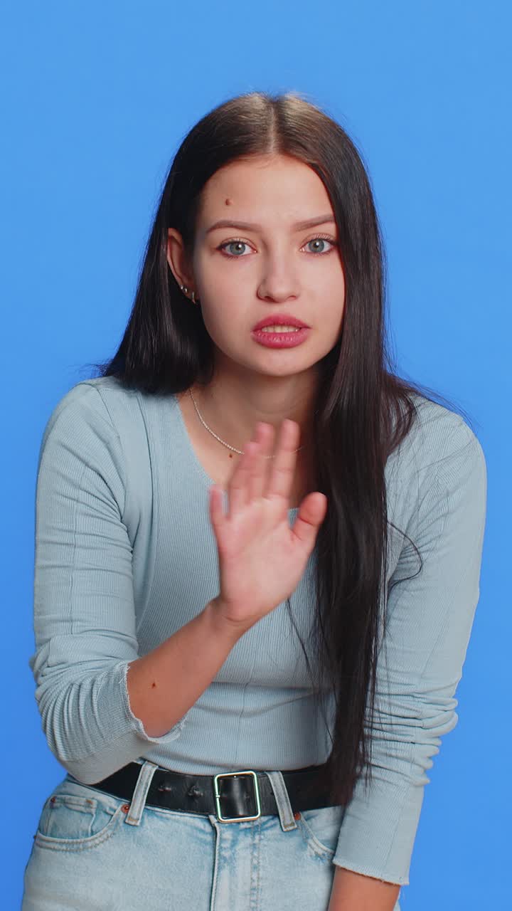 Young woman presses finger to lips makes silence gesture sign do not tells secret stop gossip