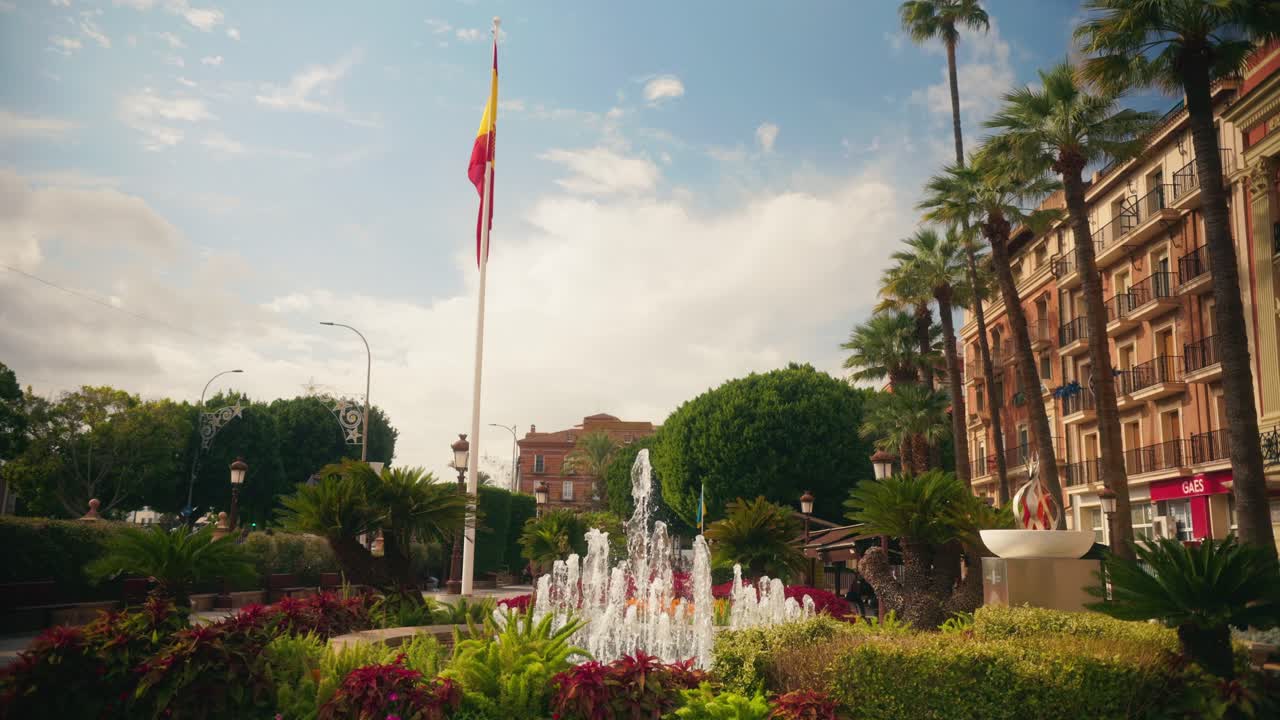 Rotonda ajardinada con fuente y asta de bandera alta.