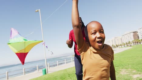 Video-of-happy-african-american-father-and-son-having-fun-with-kite-outdoors