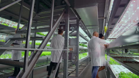 scientists and farmers work together in a team to create clean plants in an artificial environment using modern technology laptops and tablets.