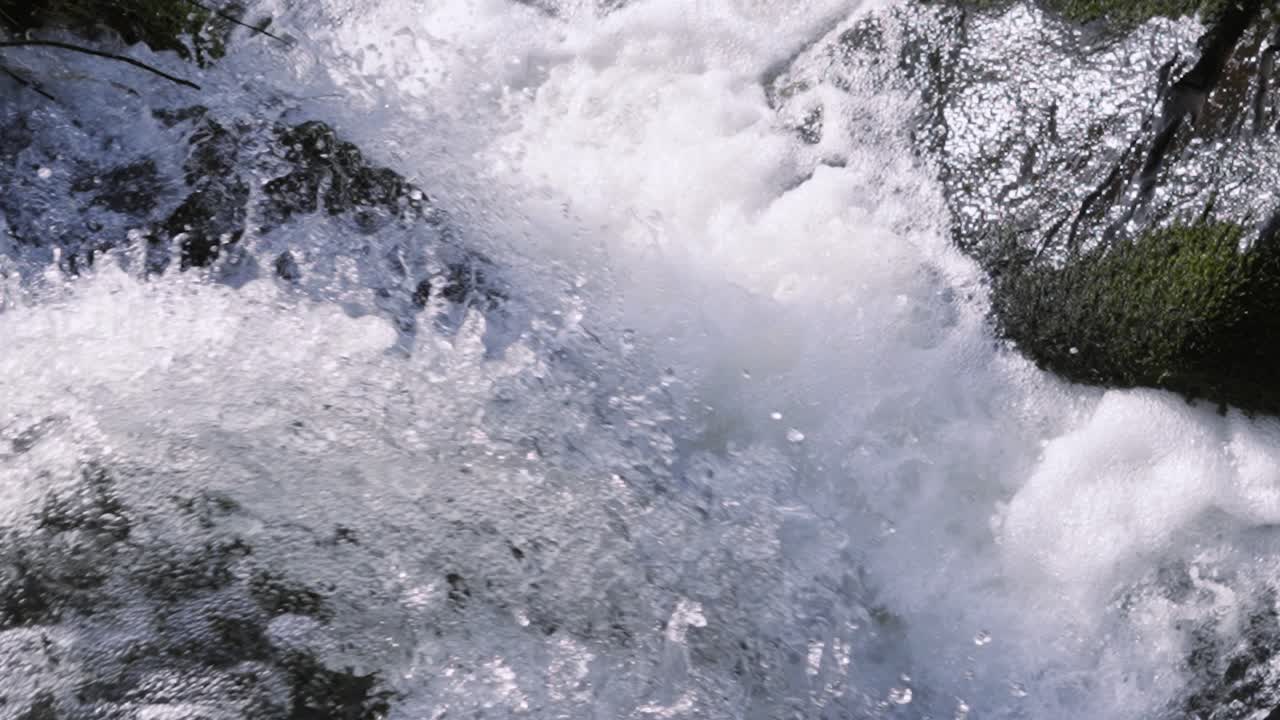 Ultra Slow Motiion Waterfall Flowing Along Powerful River with Details of Water Droplets as They Drop onto Rocks Below.