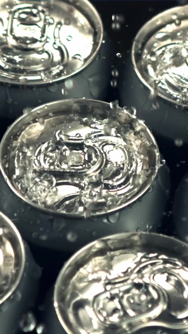 Primo piano di acqua che schizza sulla parte superiore di lattine di alluminio