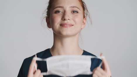 redheaded doctor in front of camera on gray background.