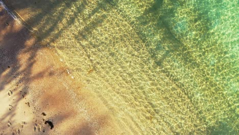 crystal-clear-sea-water-splashing-on-the-golden-sand-beach,-aerial-high-angle-seascape-,-the-tropical-beach