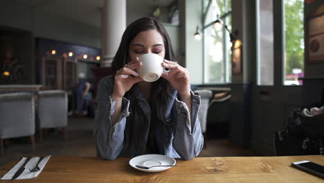 beautiful hispanic latina brunette sitting at the table having a coffee