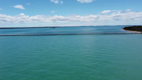 Drone-Volando-Sobre-El-Océano-Hacia-Un-Muelle-Muy-Largo